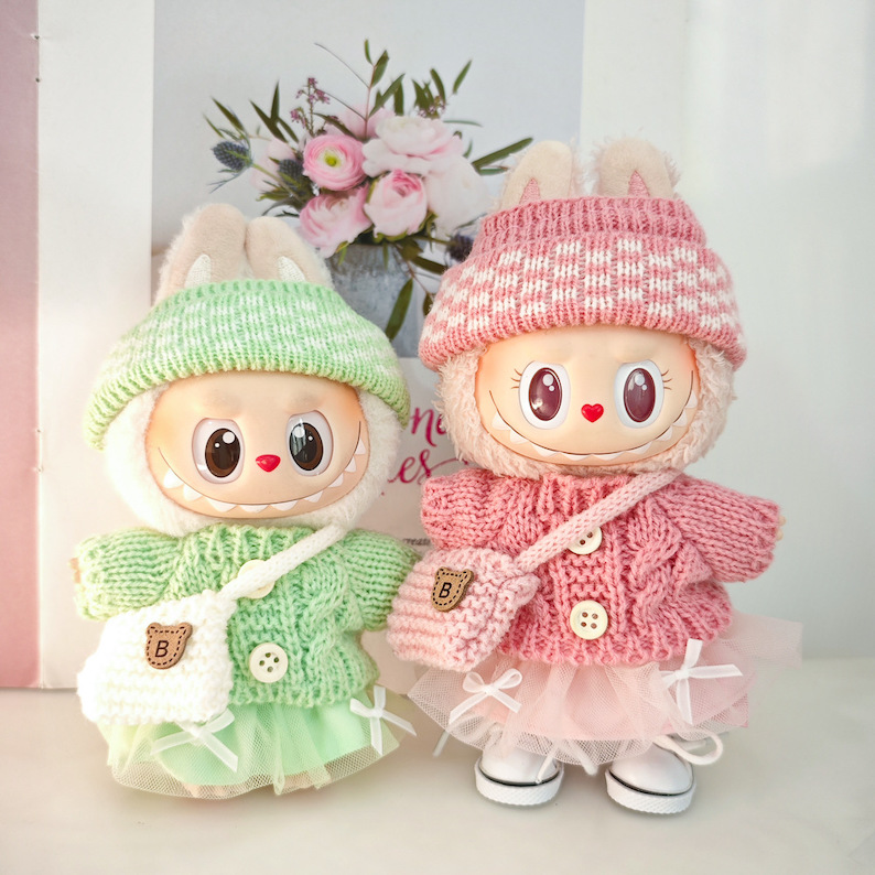 Two dolls styled in pastel knitted hats and outfits