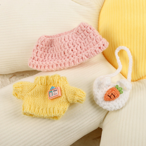 Yellow and pink knitted doll clothes with a small white bag